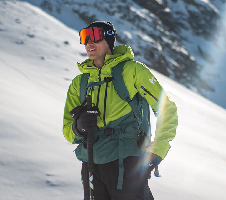 Ragazzo vestito con giacca Millet da skialp e maschera da sci Oakley