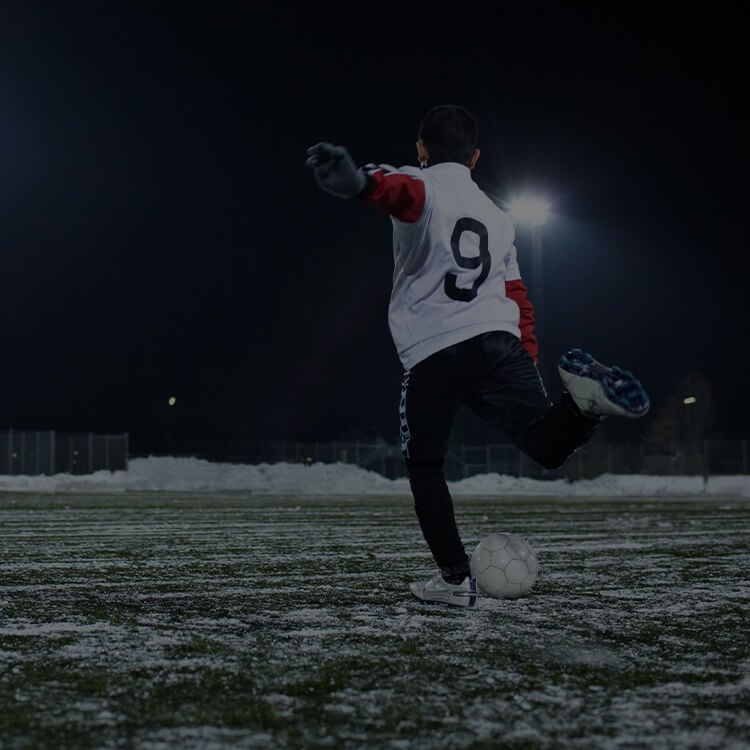 Ragazzo che gioca a calcio in inverno con la neve